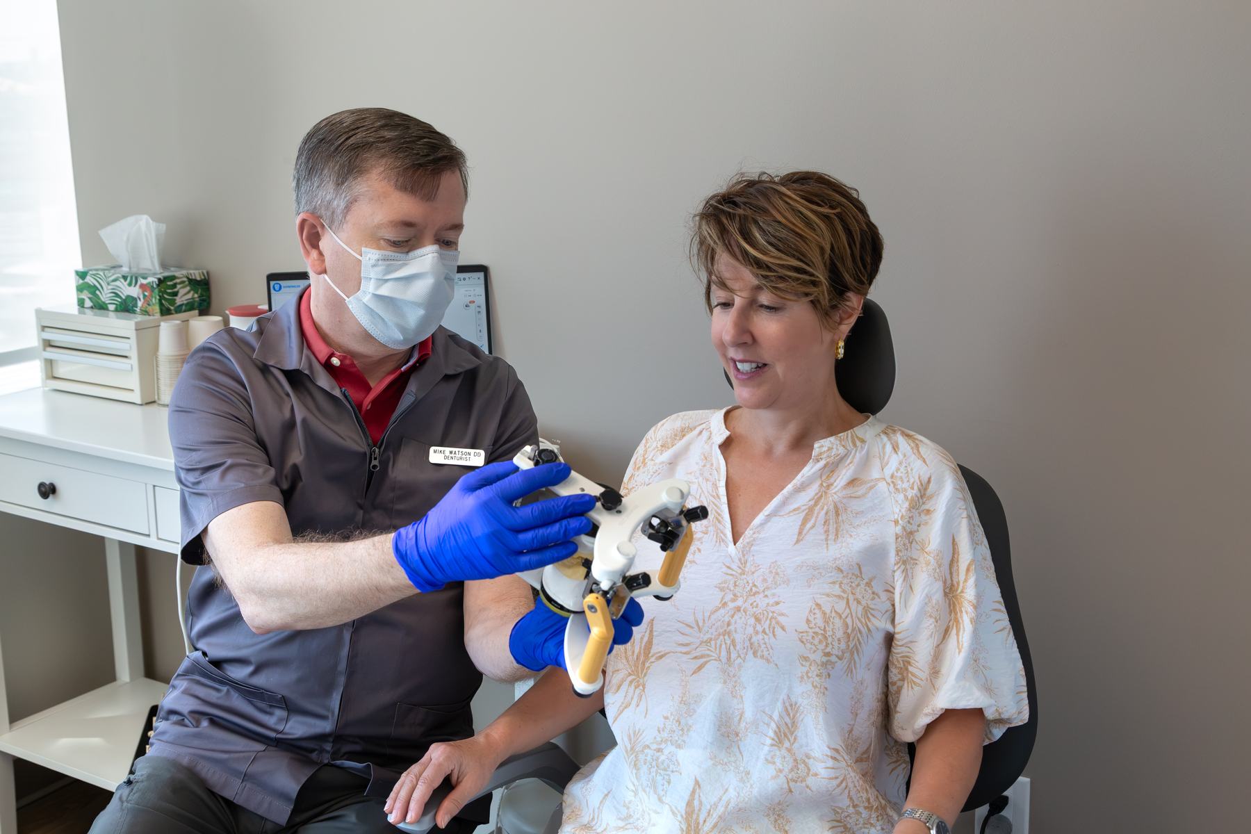 Michael Watson showing a patient a denture on an articulator