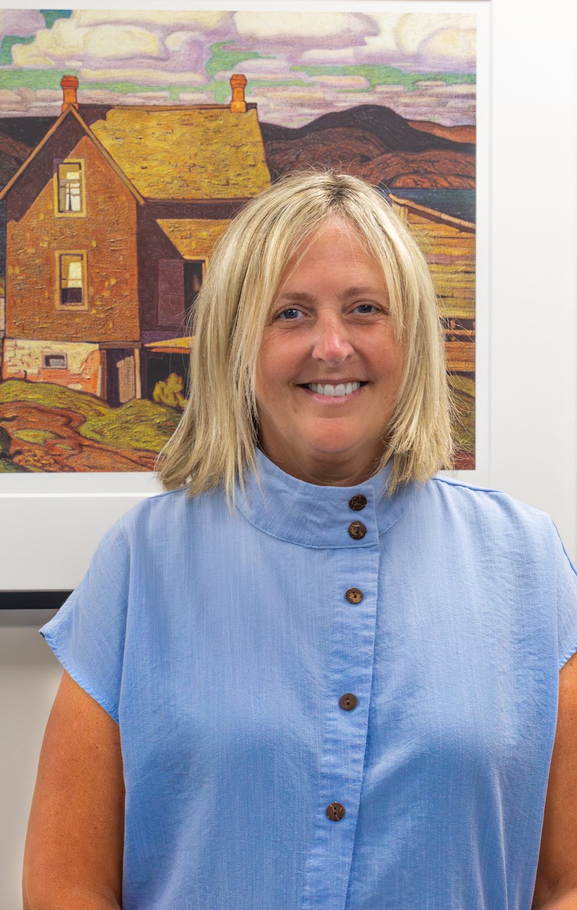 Deb Miller smiling in front of a landscape painting