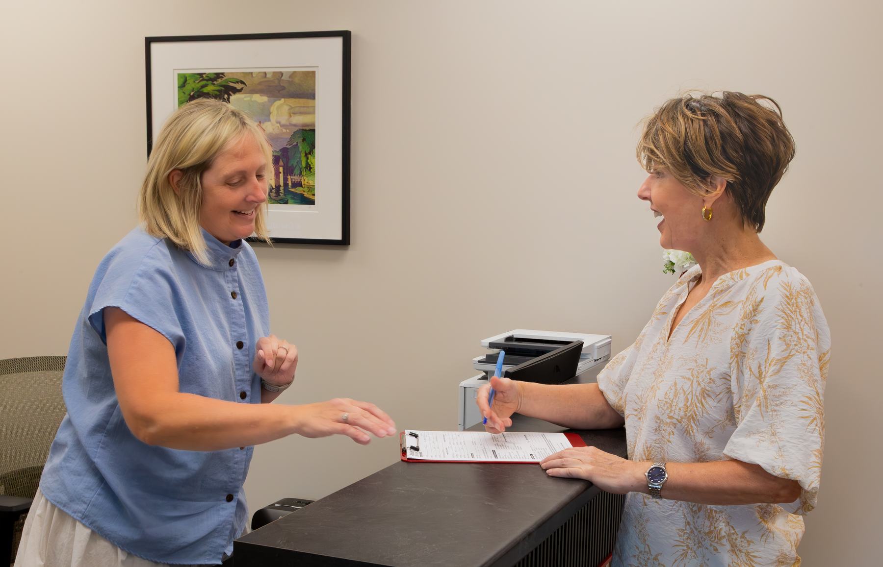 Deb Miller helping a patient with paperwork at reception